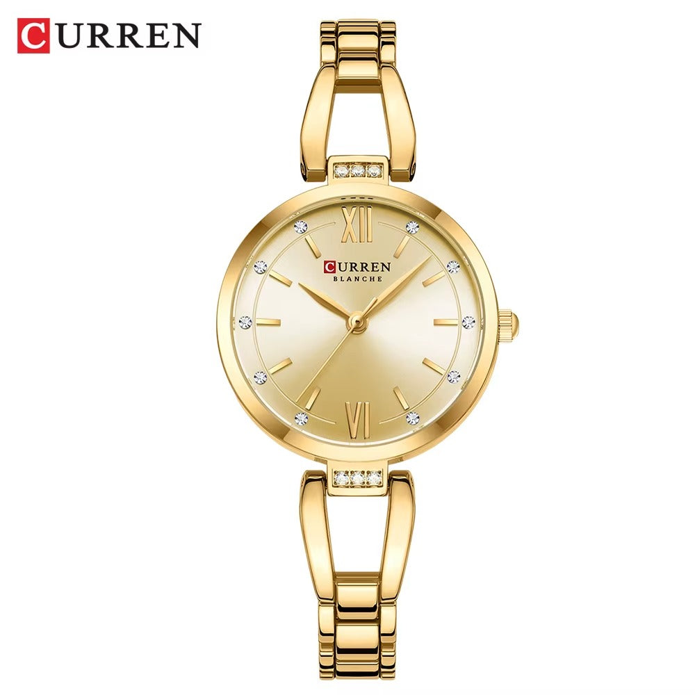 Silver women’s Curren Blanche wristwatch with gold dial, crystal hour markers, and stainless steel bracelet on white background.