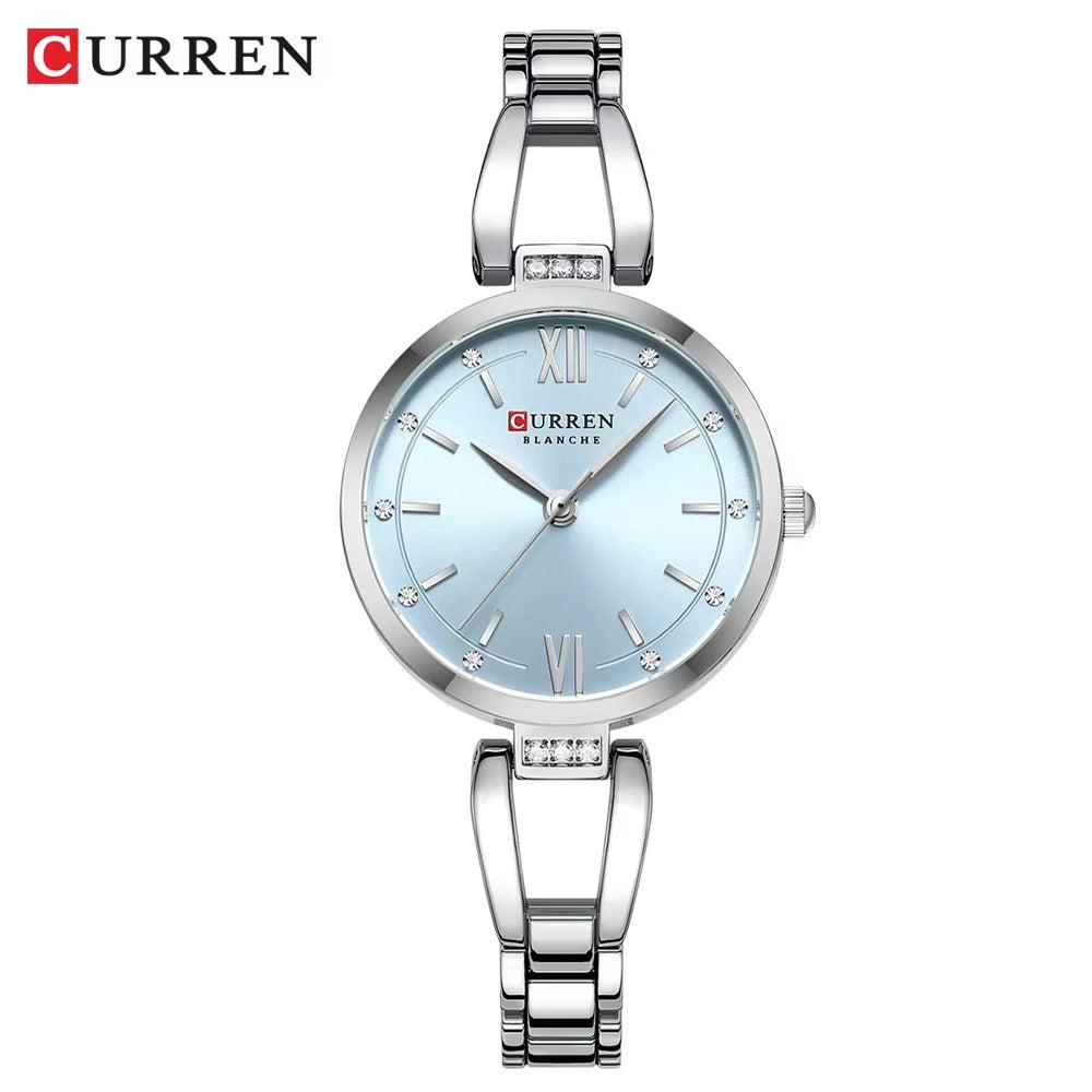 Silver women’s Curren Blanche wristwatch with sky blue dial, crystal hour markers, and stainless steel bracelet on white background.