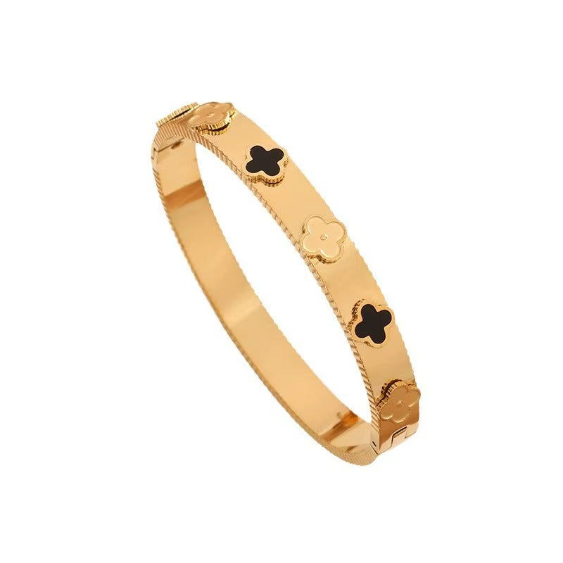 Luxury clover motif bangle bracelet in gold finish with alternating black and solid gold clover designs.